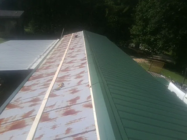 Old rusted panels beside newly installed green metal roofing — Wind Damage Roof Repair by Roofing Brothers in Gill
