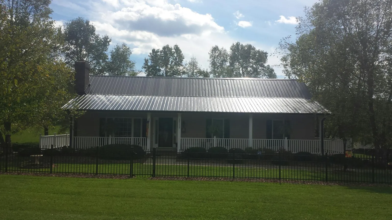 Gray metal roof on a brick ranch with a full width front porch — Gutter Guard Installation work by our crew in Gill